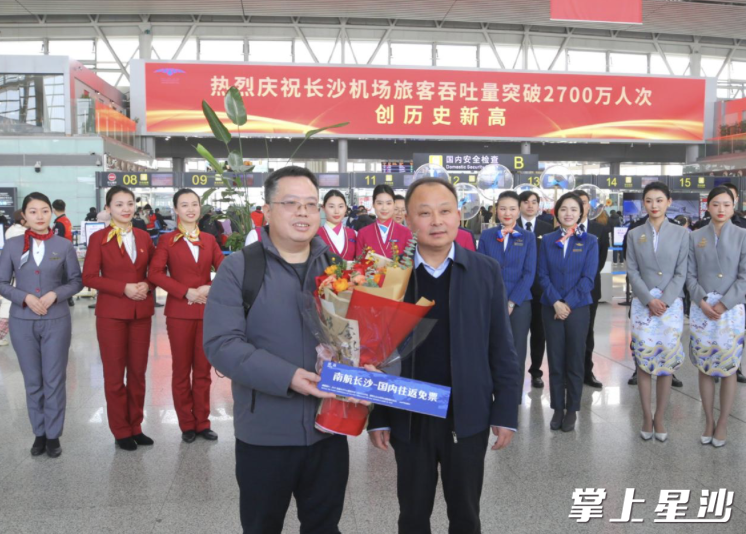 图为湖南机场集团党委副书记、总经理崔武松为幸运旅客送上鲜花。长沙机场供图