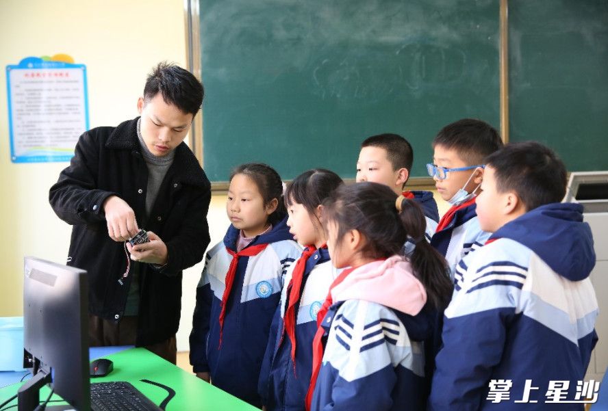 学校信息老师刘磊向学生演示红外测温报警装置如何组装和使用。