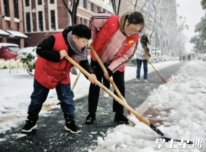 志愿者马玲带着9岁的儿子皮曦源正在奋力铲雪。