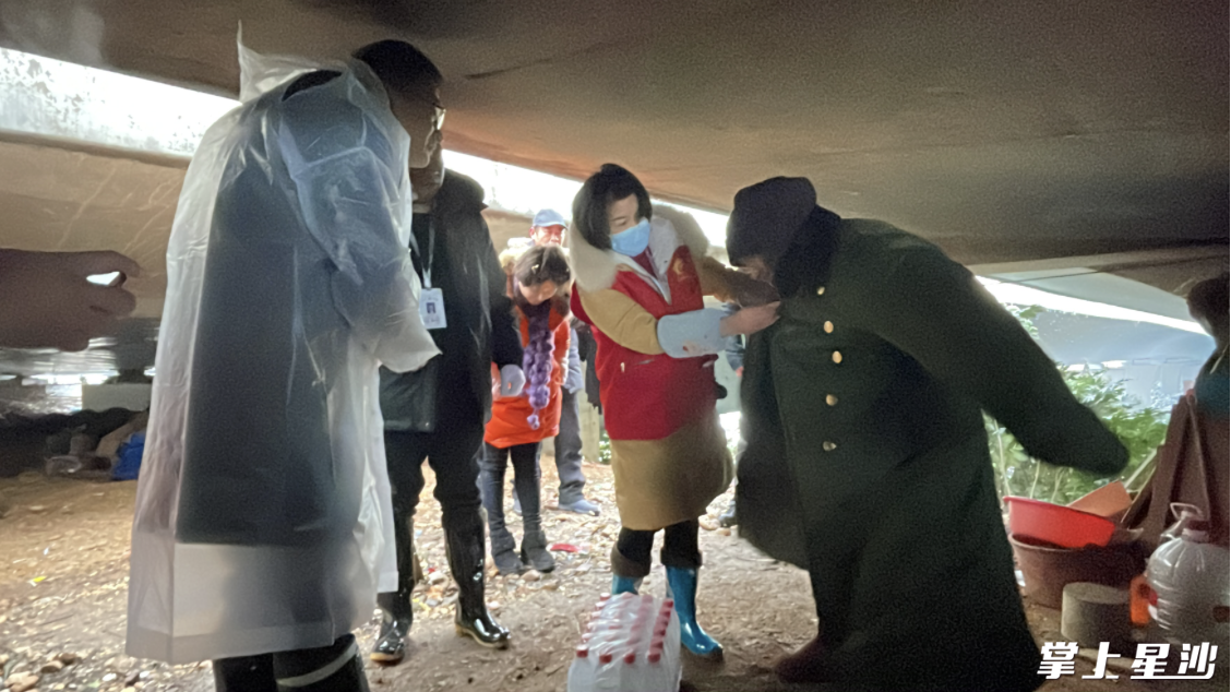 救助站工作人员给流浪人员送物资,并劝导其去救助站。张梓峰 摄