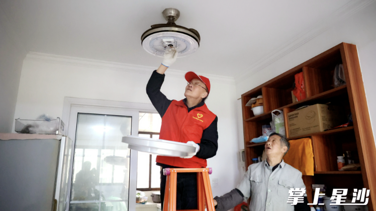 图为七旬老党员刘正良帮助居民修理电灯。