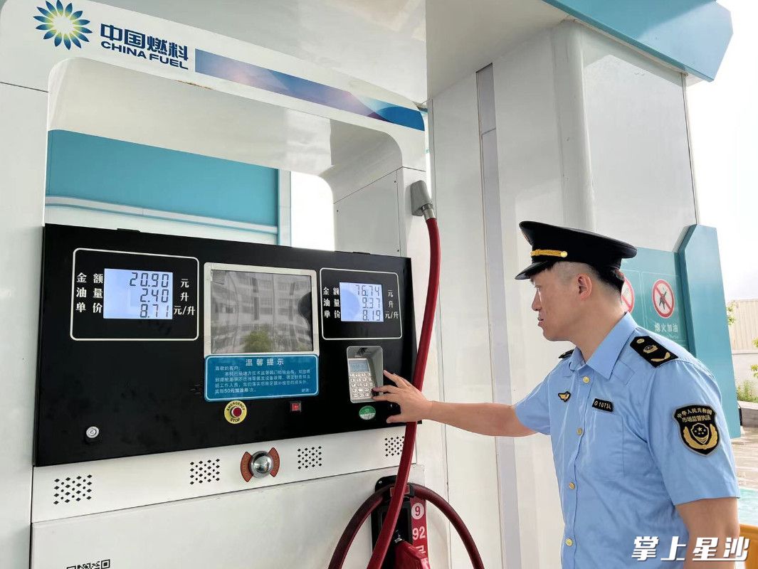 图为县市监局执法人员检查加油机。