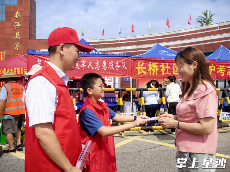 泉塘街道机关工作人员温长源带着11岁的儿子在长沙县一中考点做志愿服务。栗稳 摄