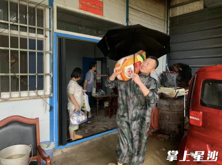 镇应急办工作人员胡胜强帮助群众转移物资。黄兴镇供图