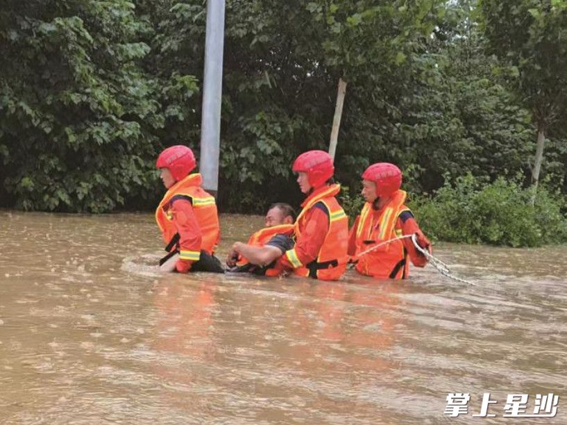暴雨中，三名消防救援人员艰难抬着被困人员，利用安全绳将其转运至安全地点。县消防救援大队供图