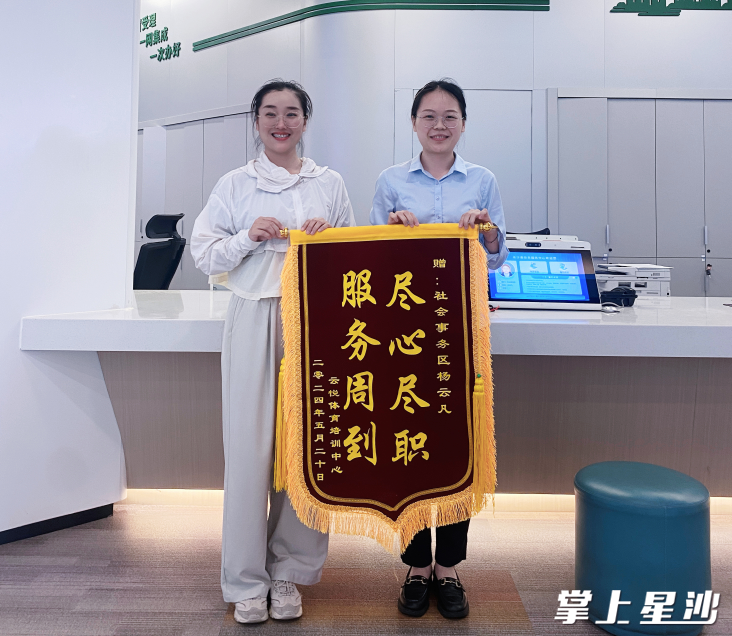 云悦体育培训中心的尹女士（左）将一面写有“服务周到，尽心尽职”的锦旗送给窗口工作人员。长沙县政务服务中心供图