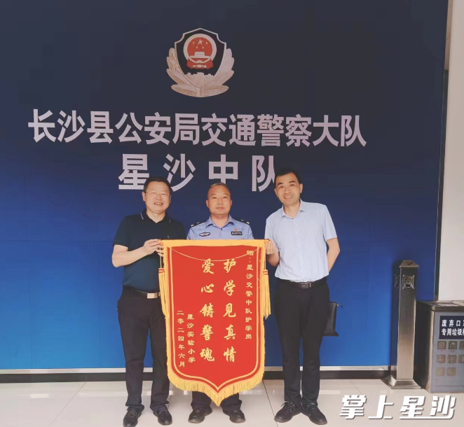 星沙实验小学校长和主任将锦旗送至长沙县公安局交警大队星沙中队指导员唐虎手中。星沙中队供图