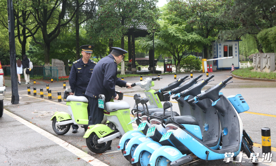 网格执法队员将乱停放的共享单车摆放至指定位置。刘萍 摄