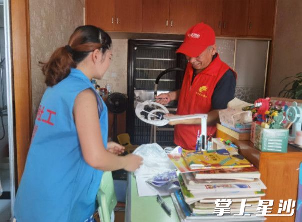 王志强（右）正在陈先明家中检修灯管。街道供图
