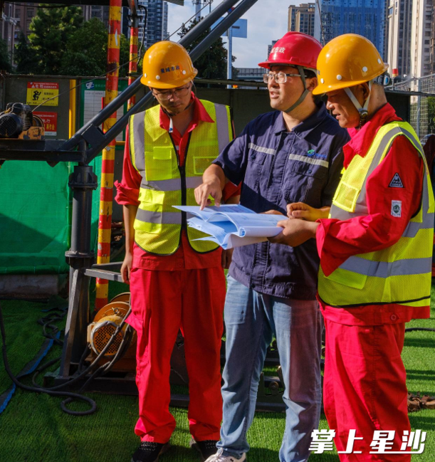 凉塘路至北斗路DN900给水改造项目现场，项目经理殷颖正向施工班组详细讲解着图纸设计情况。