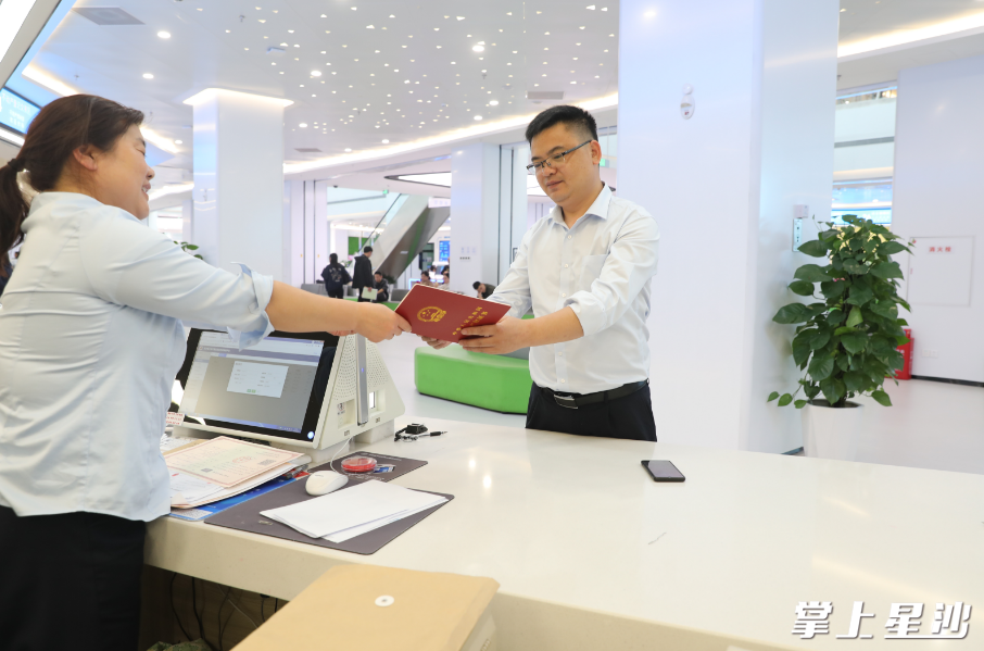长沙县首笔跨行“双预告带押过户”业务落地，中国银行星沙支行的工作人员替群众从不动产登记中心窗口领到了产权证书。彭娴 摄