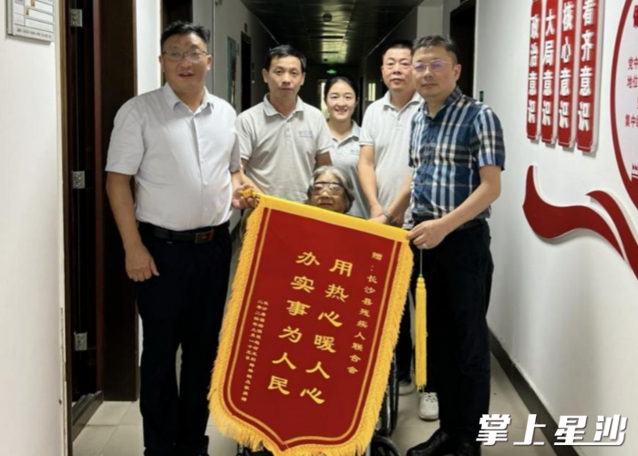 长沙县福临镇双起村的王奶奶将一面印有“用热心暖人心 办实事为人民”的锦旗送到长沙县残疾人联合会。县残联供图