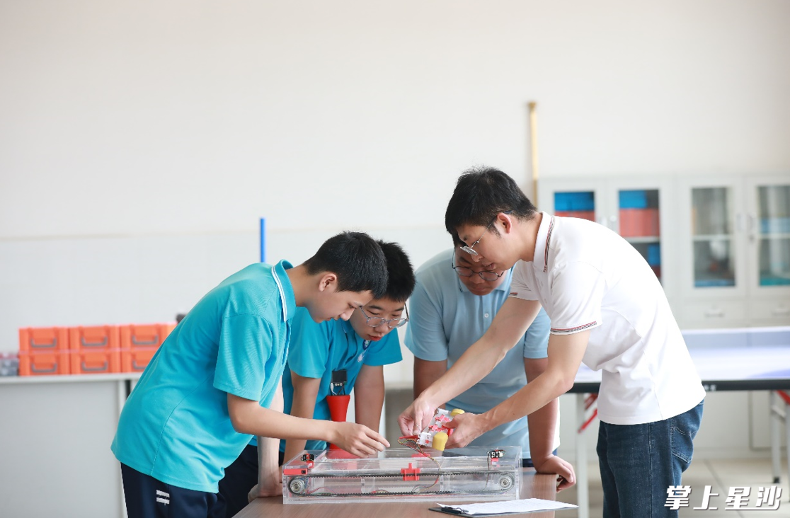 在泉塘中学创客工作室，欧镕玮和龚筱予、宁文轩、谭鱇晏一起探讨如何优化发明装置。李杰 摄