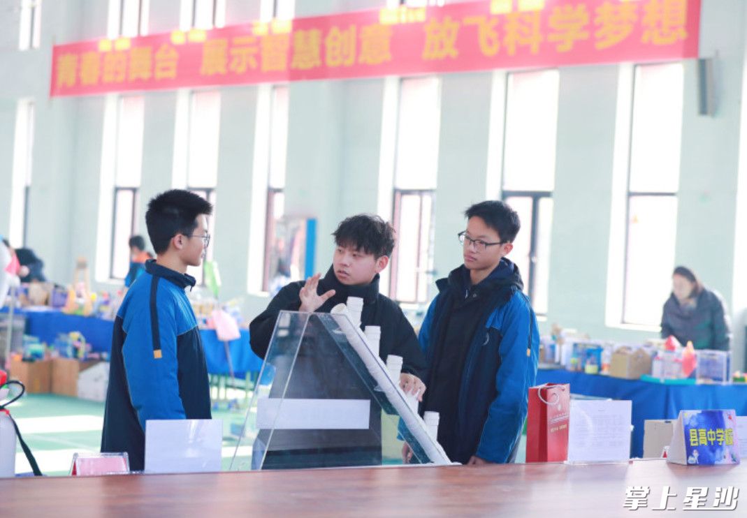 研究性学习老师甘晋宇和何润航、王宇涵交流如何优化发明装置。