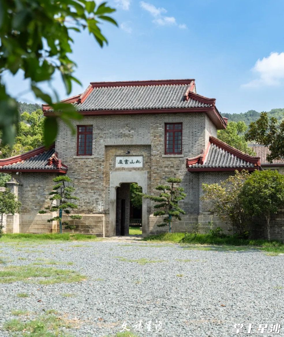 北山书屋，院内有草坪和高大古树，主楼灰砖素柱很古朴。