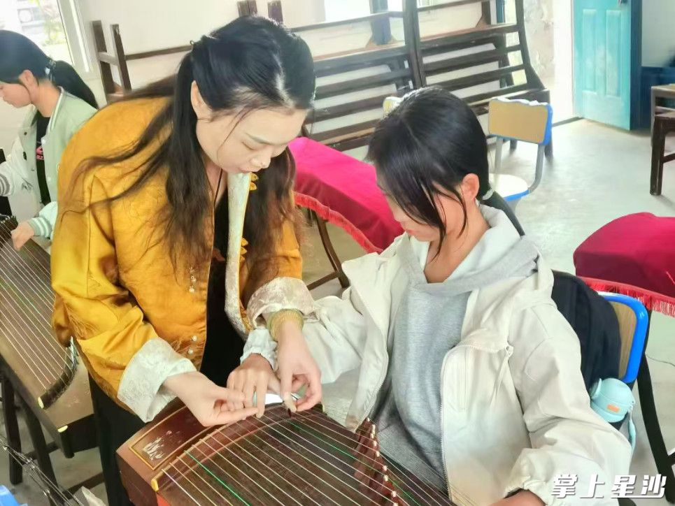 老师正在指导学生弹古筝。