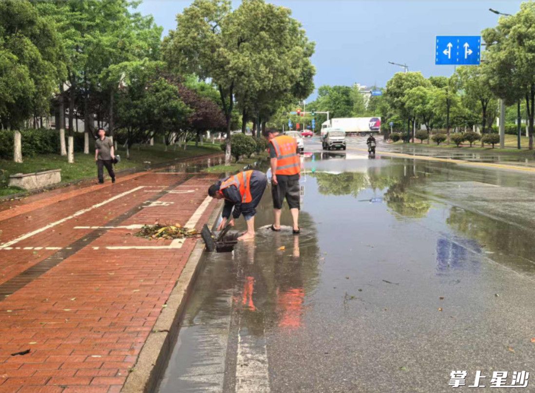 工作人员疏通道路下水道。