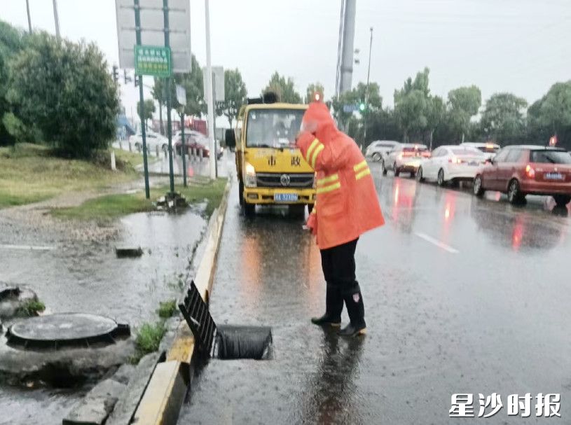 市政工人打开道路下水道篦子加快排水。㮾梨街道供图