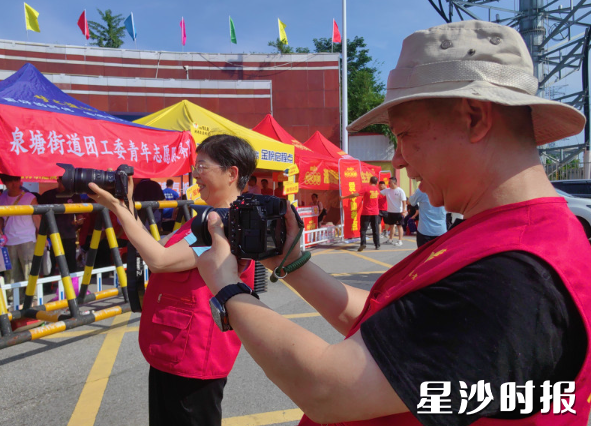 长沙县摄影家协会的曹向东（右一）、黄宇（左一）变身为“摄影志愿者”，记录考点外精彩瞬间。泉塘街道供图