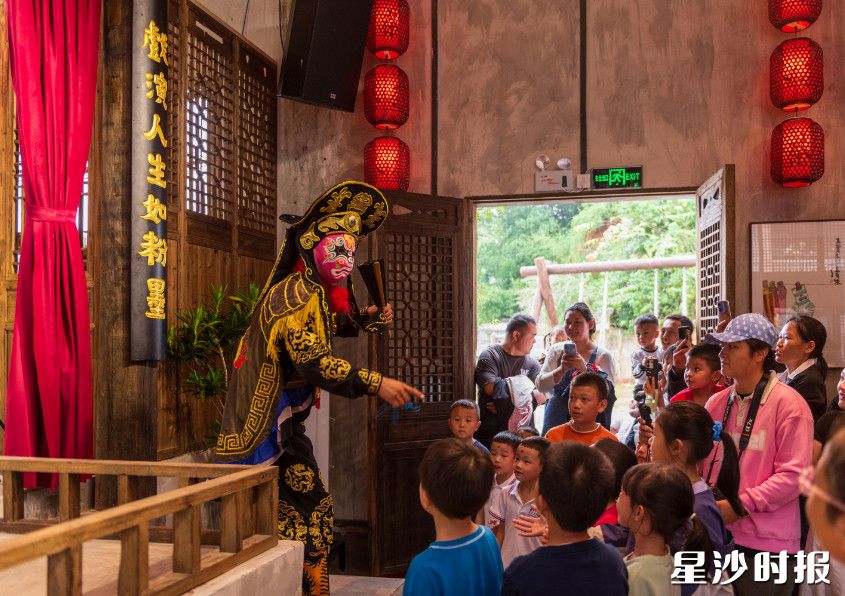精彩的变脸表演吸引众多小朋友驻足观看。