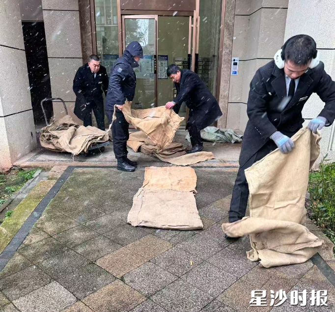 国泰九龙湾小区物业工作人员在楼栋门口撒布铺路，预防滑倒。
