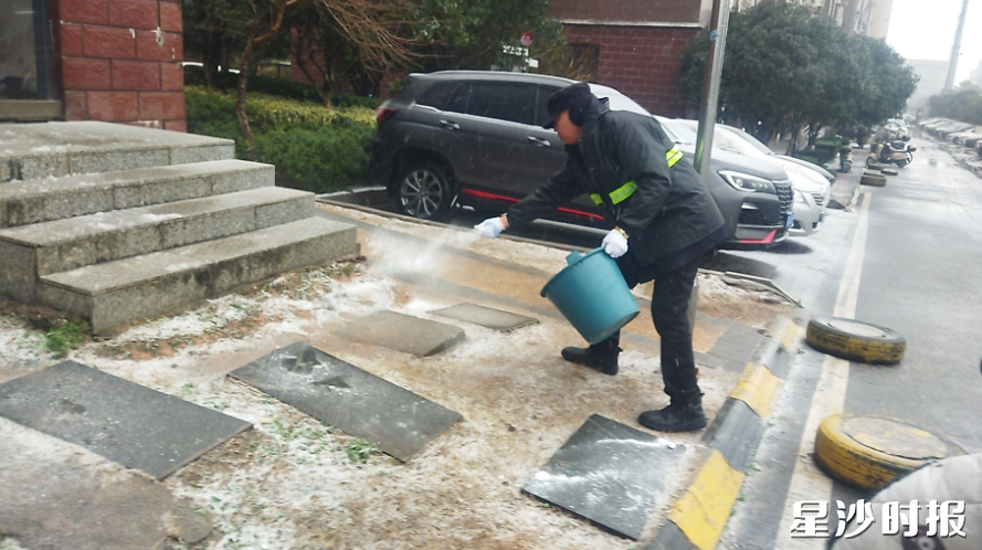 豪都至尊小区物业工作人员在小区内部道路撒盐。