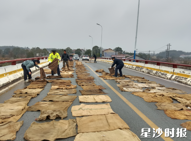 青山铺综合行政执法大队队员与镇政府、洪河村干部一道，对桥面铺设麻袋和撒盐作业，确保道路交通和人民群众出行安全。