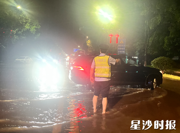 暴雨中，执法队员为车辆指引方向。县行政执法局供图