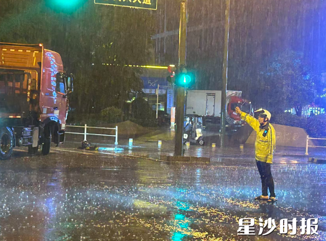 长沙县公安局交管大队警员冒雨值守，指挥过往车辆。