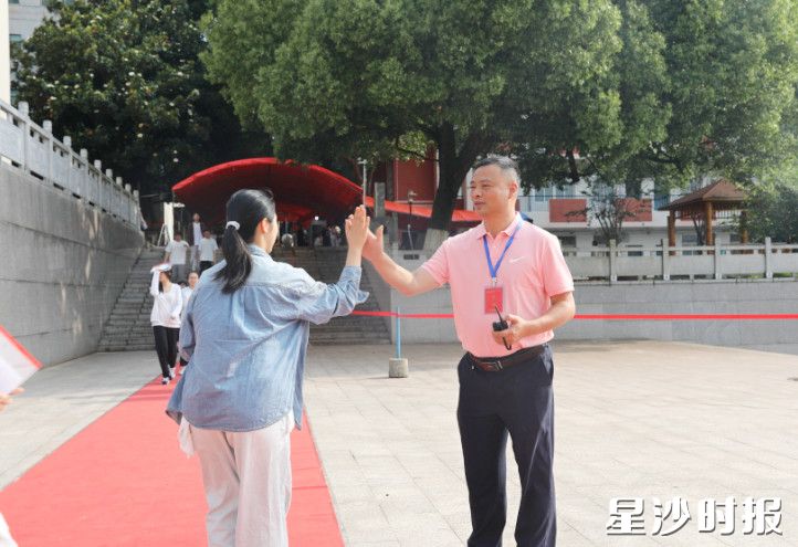 长沙县第一中学校长为步入考场的考生击掌鼓劲，寓意“一击得胜”。文雅丽 摄