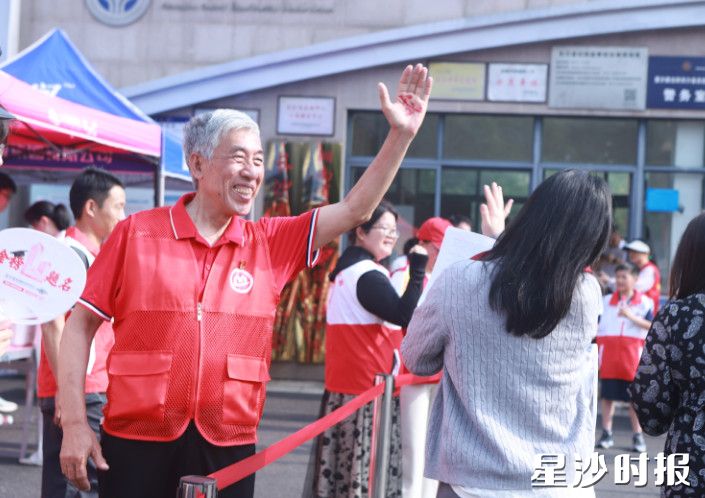 长沙县实验中学门口，“湖南好人”陈小明与高考考生们击掌，祝福考生马到功成！ 刘萍 摄