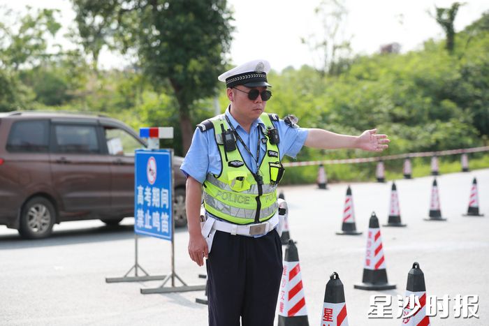 在黄兴镇长沙市明达中学考点附近，交警引导车辆出行，为考试静音。李杰 摄