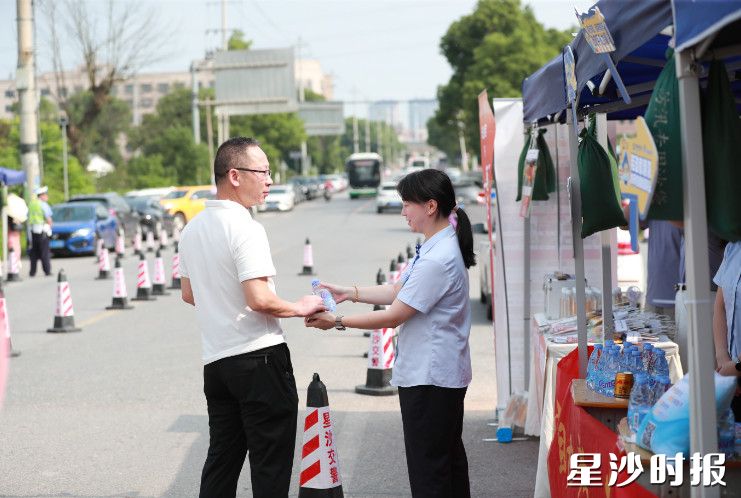 在黄兴镇长沙市明达中学考点，志愿者为家长送水。李杰 摄