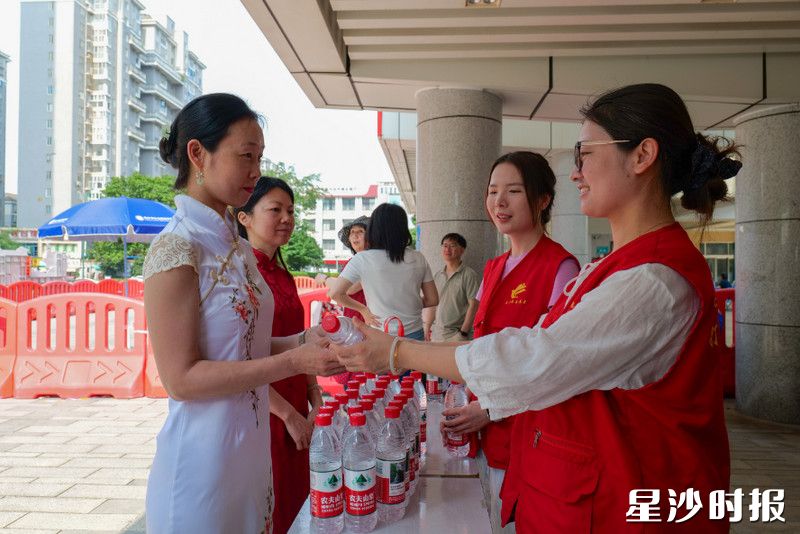 在长沙市弘益高级中学考点，泉塘街道青年志愿者暖心服务考生家长。陈茂 摄