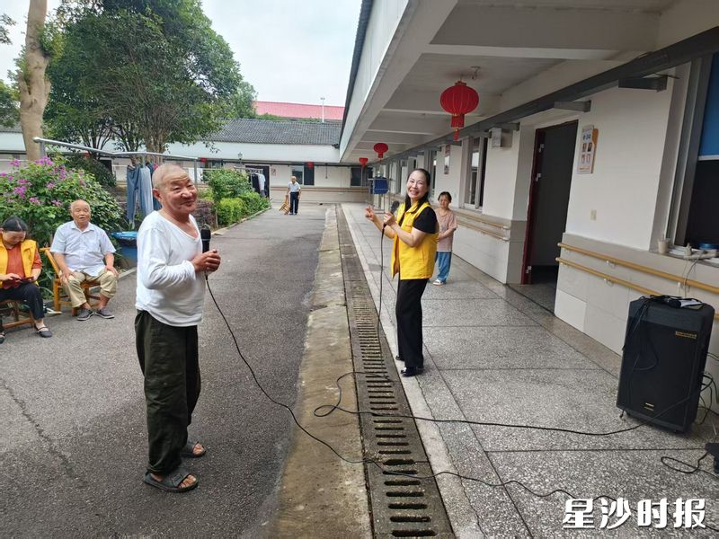 义工与老人们一起进行唱歌表演。